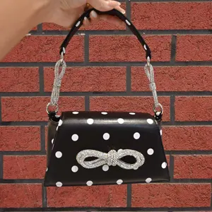 Schwarze Handtasche Detail mit Polka Dots, funkelnder Strass-Schleife und Kette.