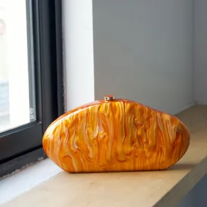 Acrylic evening clutch bag with unique irregular marble pattern and metal lock closure.