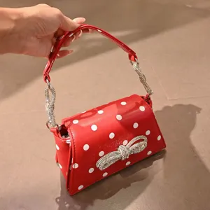 Nahaufnahme der roten Pünktchen Umhängetasche mit funkelnder Strass-Schleife und Kette.