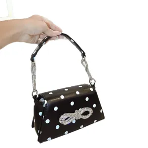 Schwarze Handtasche mit Polka Dots und funkelnder Strass-Schleife als elegante Schultertasche.