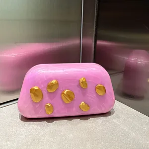 Detailansicht der rosa marmorierten Acryl-Clutch mit einzigartigen Goldklumpen.