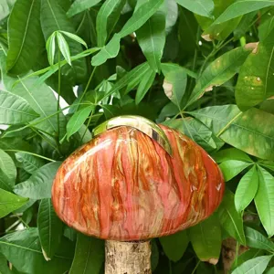 Nahaufnahme einer einzigartigen braunen Acryl-Handtasche auf einem Baumstumpf im Wald.