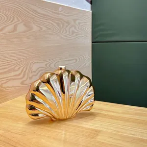 Gold metallic shell clutch bag detail, elegant evening party purse, unique acrylic design.