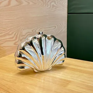 Silver metallic shell shaped evening clutch bag detail view, modern minimalist fashion accessory.
