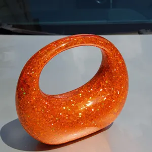 Orange glitter crescent bag detail view, sparkling evening shoulder handbag close-up.