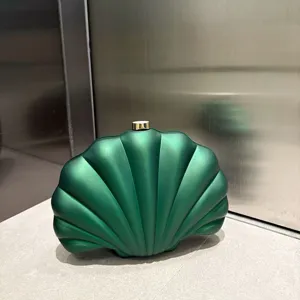 Dark green acrylic shell clutch bag detail, matte texture surface with gold clasp closure.