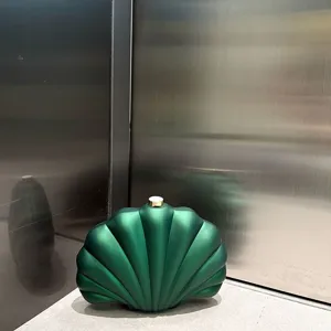 Green matte acrylic shell clutch bag detail showing unique shape and metallic clasp.