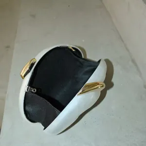 Detailansicht der weißen Hartschalen-Clutch mit elegantem goldfarbenem Metallverschluss innen.