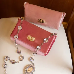 Roze fluwelen schoudertas met fonkelende strass-kettingen en een elegante metalen sluiting.