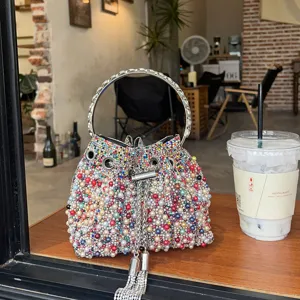 Bolso cubo de perlas y pedrería estilo francés con asa de metal y diseño de borla de cadena.