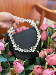 Black satin evening clutch featuring a stunning crystal rhinestone ring handle and elegant design.