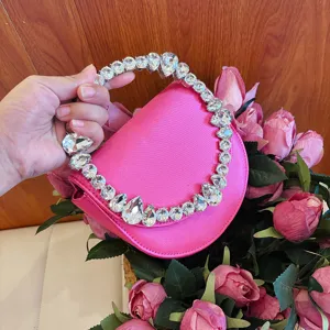 Close-up detail of a bright pink satin evening handbag featuring a stunning rhinestone ring handle.