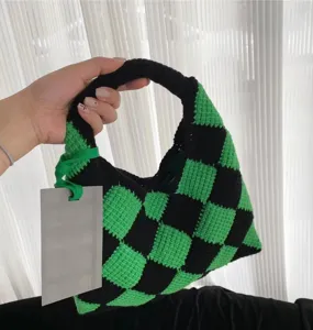 Close-up detail of the green and black checkered hand-knitted crochet basket bag handle.
