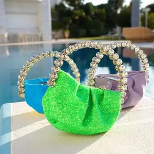 Mini evening bag with dazzling crystal handle and glitter pleated design. Perfect party accessory.