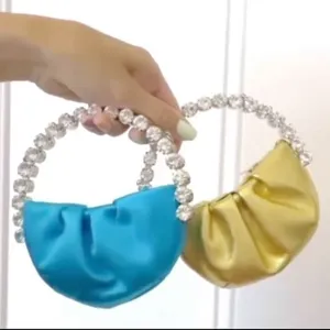 Detail shot showing mini pleated evening handbags featuring stunning rhinestone circle handles.