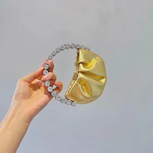 Gold pleated mini evening bag featuring a striking crystal rhinestone circle handle detail.