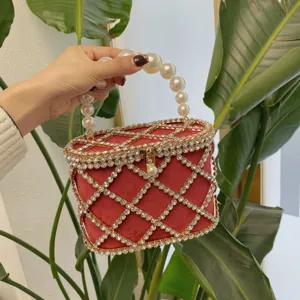 Close-up detail of red velvet rhinestone evening bag featuring pearl handle and crystal grid.