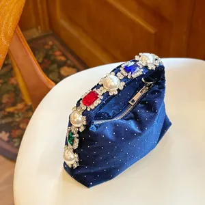 Detalle de primer plano del bolso de noche de terciopelo azul con perlas y cristales.