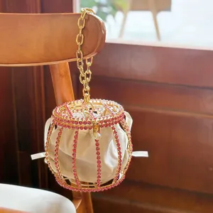 Rhinestone birdcage bucket bag with gold chain handle and white velvet inner pouch.