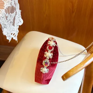 Detalle del bolso de noche de terciopelo, clutch rojo con perlas y estrás, cadena elegante.
