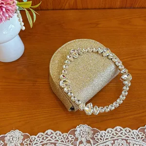 Close-up of a glamorous gold glitter evening clutch with a sparkling rhinestone ring handle.