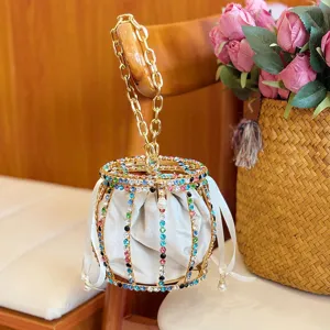 Detail view of luxury rhinestone metal cage handbag with white velvet pouch and gold chain handle.