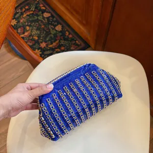 Close-up detail of blue rhinestone evening clutch bag with sparkling crystals and gold chain link.