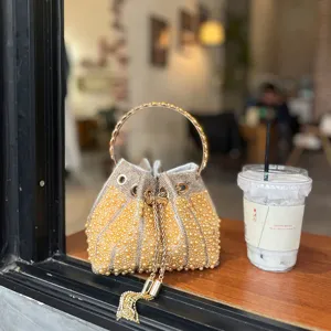 Bolso cubo minimalista francés de perlas con asa redonda de metal y diseño de cordón.