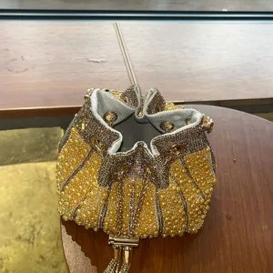 Vista detallada del bolso saco elegante con perlas y pedrería con cierre de cordón.
