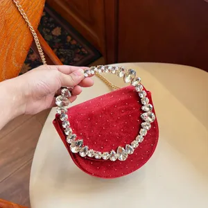 Detailed view of luxury red velvet evening bag with sparkling crystal handle and gold chain.