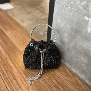Vista detallada del bolso cubo negro de cuentas con asa de anillo metálico y borla.