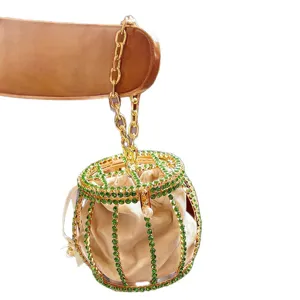 Elegant metal rhinestone cage bucket bag with gold chain, velvet inner pouch, and pearl accent.
