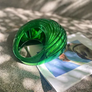 Green swirled acrylic handbag detail shot, showcasing the unique spiral design and glossy texture.