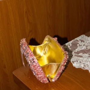 Détail de pochette rigide en cristaux roses, strass étincelants avec intérieur métal doré.