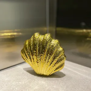 Detailed view of the metallic gold shell evening clutch bag, showing glossy textured surface.