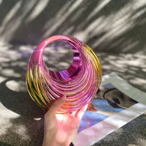 Close-up view of the shiny metallic iridescent acrylic handbag showing unique spiral design details.