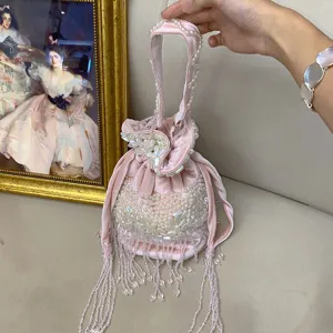 Gros plan sur le sac seau en velours rose perlé avec des détails de pampilles en cristal.