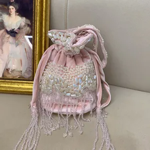 Vue détaillée du sac seau en velours rose avec perles faites à la main et franges de cristal.