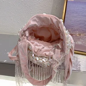 Détail de sac seau en velours rose, perles faites main et franges en cristal chic.