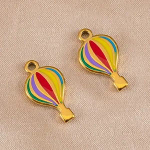 Detalle de primeros planos de dijes metálicos de globo aerostático de esmalte para joyería DIY.