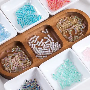 Vue détaillée de perles de bugle en verre transparent coloré 4x8mm pour fabrication de bijoux.