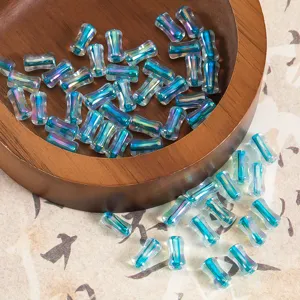 Gros plan de perles de verre bleues irisees dans un bol en bois pour bijoux faits main.