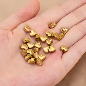 Primo piano dettagliato di piccole perle a cuore dorate con bordo in pizzo per bigiotteria.