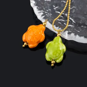 Ceramic turtle pendant details, glossy orange and green finish with gold stainless steel bead chain.