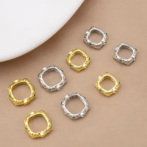 Detailed view of square ornate metal jewelry connectors with green stones for DIY crafting.