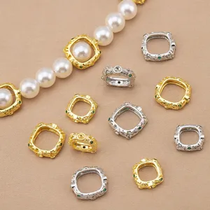 Detailed view of gold and silver square filigree connector beads with green stones for DIY jewelry.