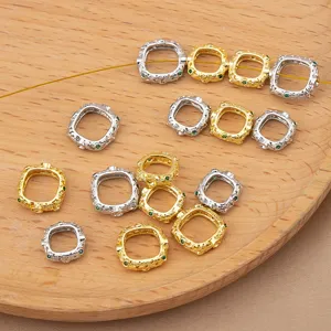 Close-up of ornate square metal spacer beads with green gems, perfect for DIY jewelry making.