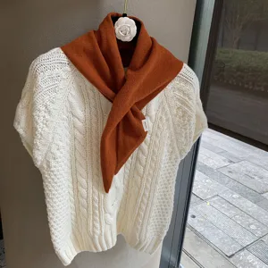 Knit triangle scarf and white sweater detail, soft texture and elegant style for autumn wear.