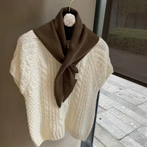 Detailed view of soft brown knitted triangular scarf, cozy autumn neck wrap, elegant style.