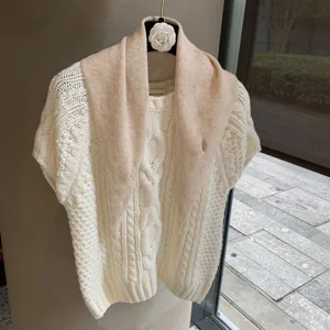 Close-up of a cozy white cable-knit short sleeve sweater with a soft beige triangle scarf detail.
